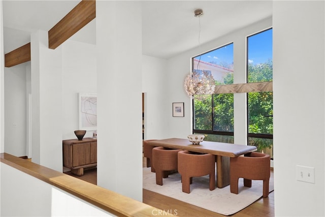 dining area featuring hardwood / wood-style floors, a notable chandelier, and beam ceiling