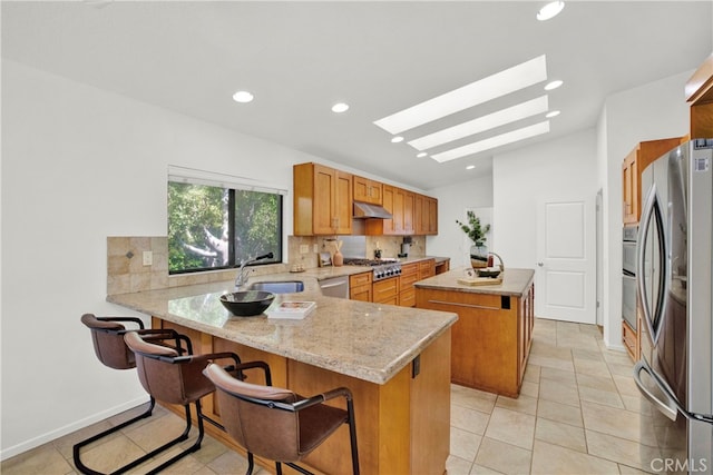 32701 Via Palacio, Rancho Palos Verdes, CA 90275 - kitchen with appliances with stainless steel finishes, under cabinet range hood, a peninsula, a kitchen island, and a skylight