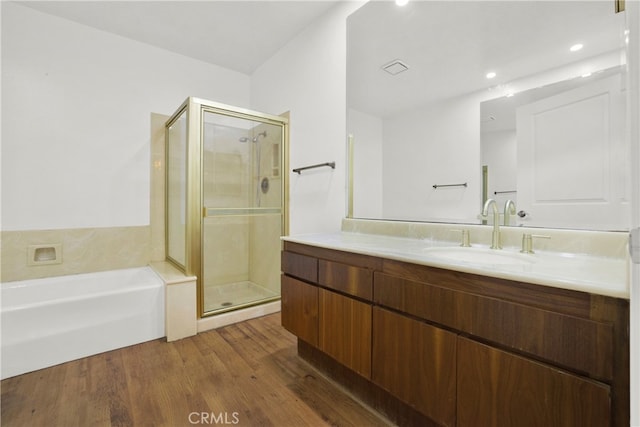 bathroom featuring plus walk in shower, vanity, and hardwood / wood-style flooring