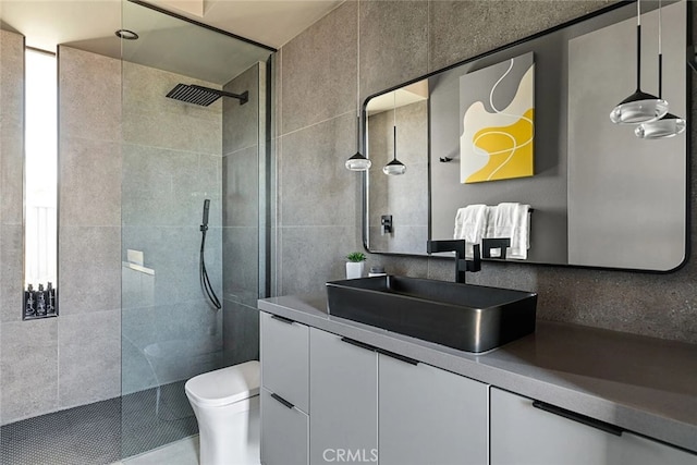 bathroom featuring toilet, vanity, and tiled shower