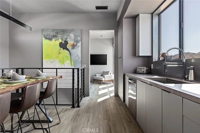 kitchen featuring dishwasher, sink, white cabinetry, and light hardwood / wood-style flooring