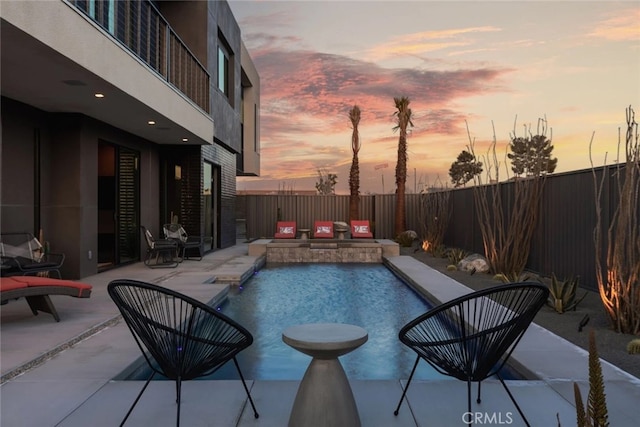 pool at dusk with a patio area