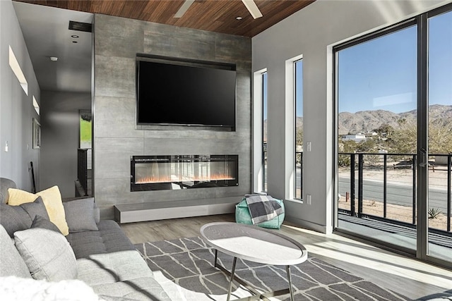 living room with wood-type flooring, a large fireplace, and wood ceiling