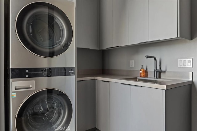 clothes washing area featuring cabinets, stacked washer and clothes dryer, and sink