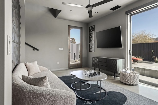 living room featuring ceiling fan, plenty of natural light, and concrete flooring