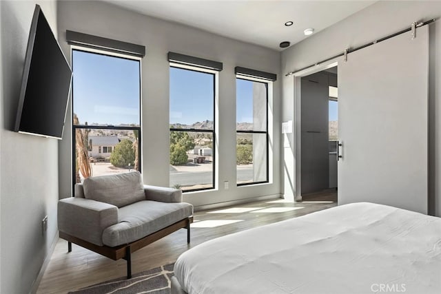 bedroom with hardwood / wood-style flooring and a barn door