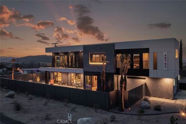 back house at dusk with a mountain view and a balcony