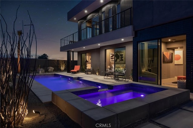 pool at dusk with a patio area and an in ground hot tub