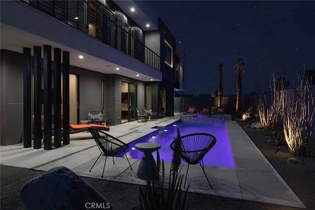 pool at twilight with a patio area and an in ground hot tub