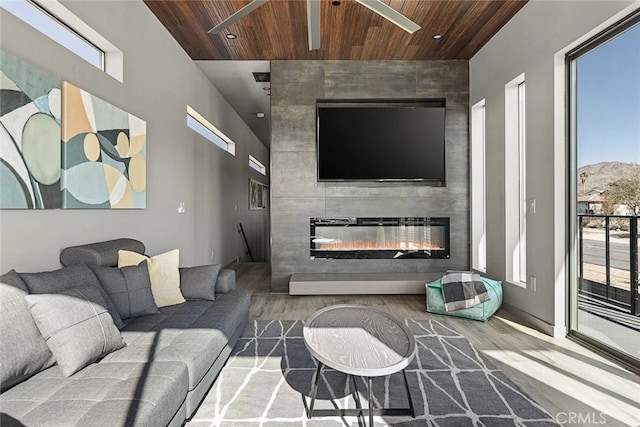 living room with hardwood / wood-style floors, a tiled fireplace, and wooden ceiling