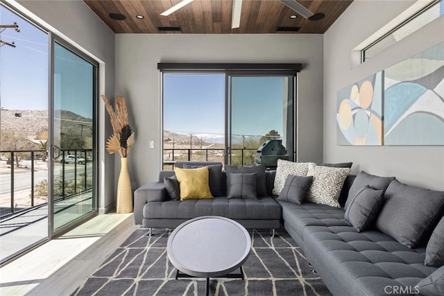 living room with ceiling fan, wood-type flooring, a mountain view, and wood ceiling