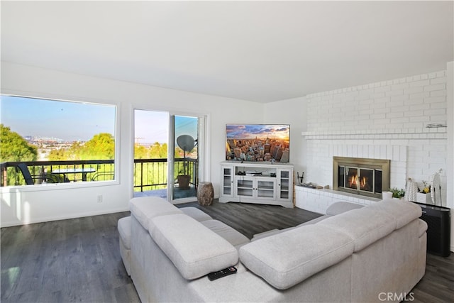 living room featuring a brick fireplace and dark hardwood / wood-style floors