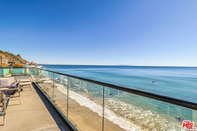 balcony featuring a view of the beach and a water view