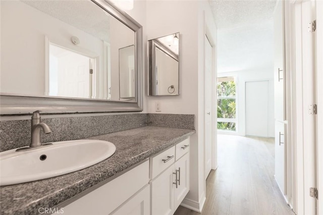 bathroom with hardwood / wood-style floors, vanity, and a textured ceiling