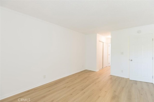 unfurnished room with light hardwood / wood-style floors and crown molding