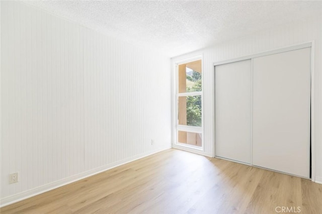 unfurnished bedroom with a closet, light hardwood / wood-style flooring, and a textured ceiling