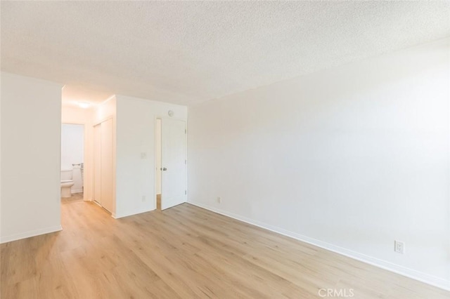 empty room with a textured ceiling and light hardwood / wood-style flooring