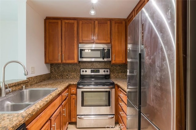 kitchen with backsplash, light stone countertops, sink, and appliances with stainless steel finishes