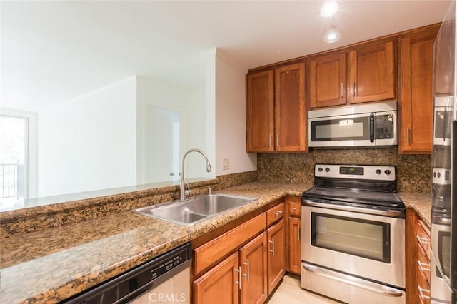 kitchen with decorative backsplash, sink, light stone countertops, and stainless steel appliances