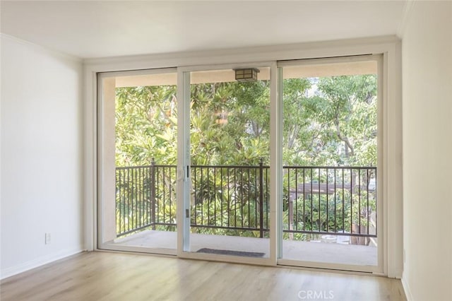 doorway to outside featuring floor to ceiling windows, light hardwood / wood-style floors, and ornamental molding