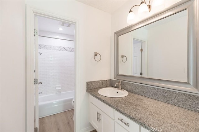 full bathroom featuring hardwood / wood-style flooring, vanity, toilet, and tiled shower / bath combo