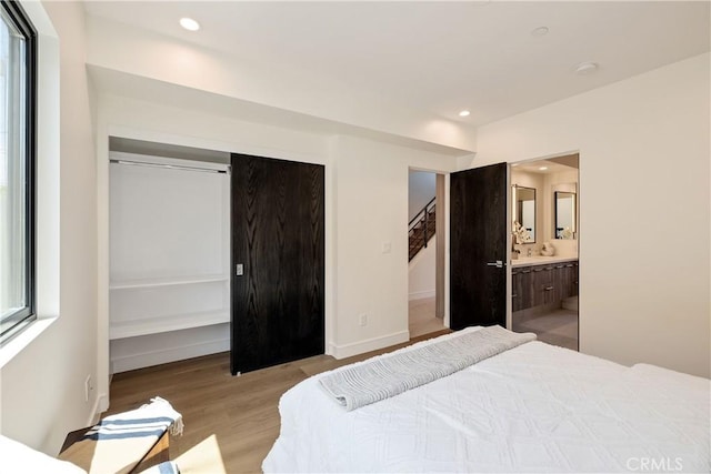 bedroom featuring connected bathroom and light hardwood / wood-style floors