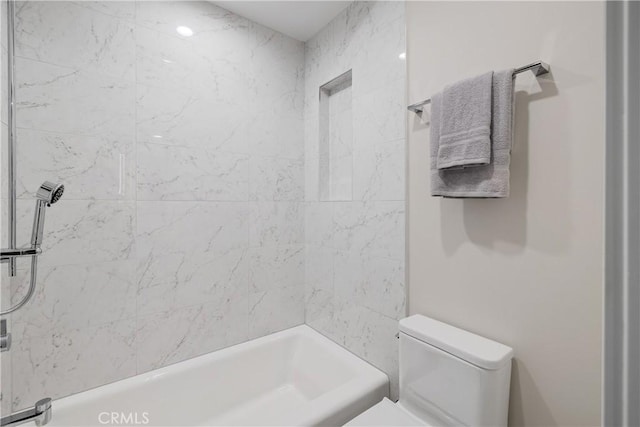 bathroom with tiled shower / bath combo and toilet