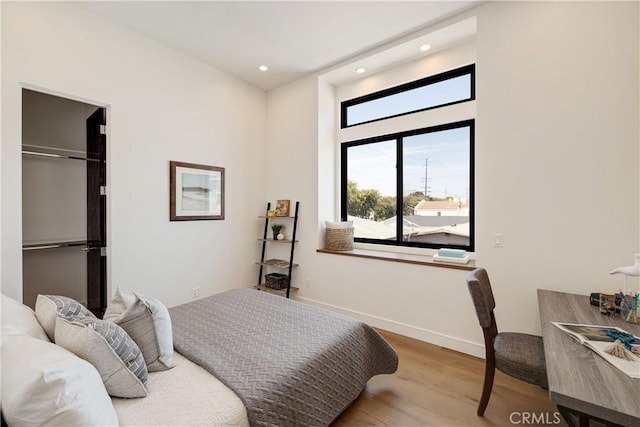 bedroom featuring a closet, a spacious closet, and light hardwood / wood-style flooring