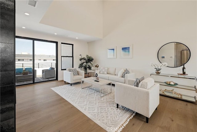 living room with wood-type flooring and a towering ceiling