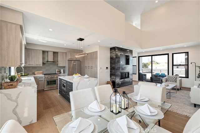 dining room featuring a fireplace, a towering ceiling, light hardwood / wood-style floors, and sink