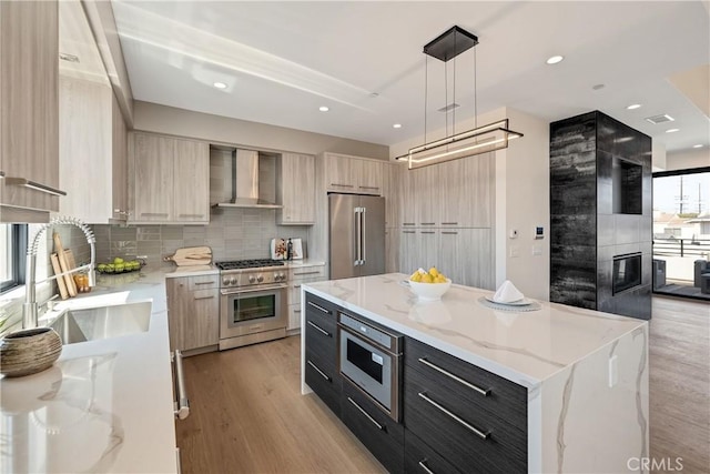 kitchen with pendant lighting, a center island, high quality appliances, wall chimney range hood, and sink