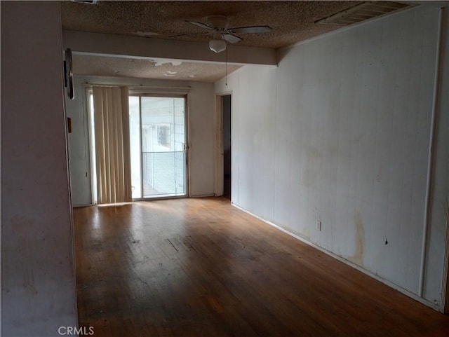 spare room featuring hardwood / wood-style flooring, ceiling fan, and wood walls