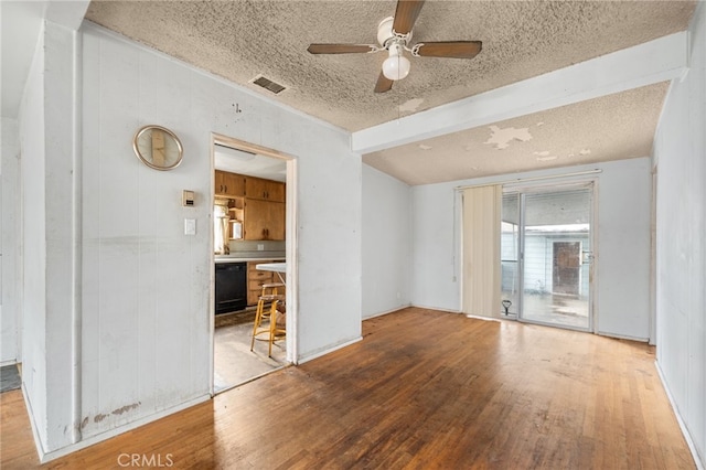 empty room featuring ceiling fan, beam ceiling, hardwood / wood-style floors, and a textured ceiling