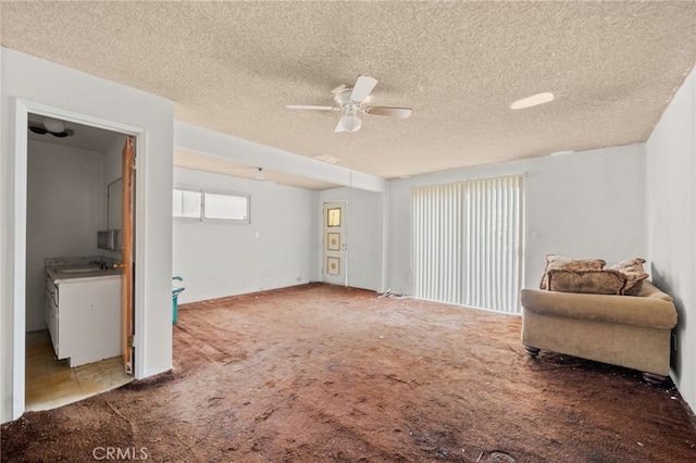 unfurnished room featuring ceiling fan, sink, light carpet, and a textured ceiling