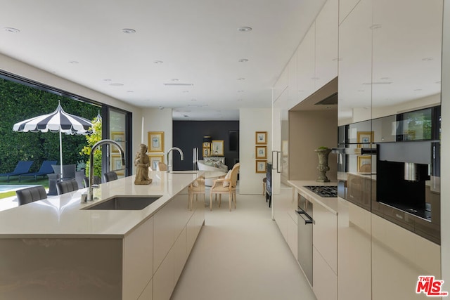 kitchen featuring white cabinetry, a center island with sink, and sink