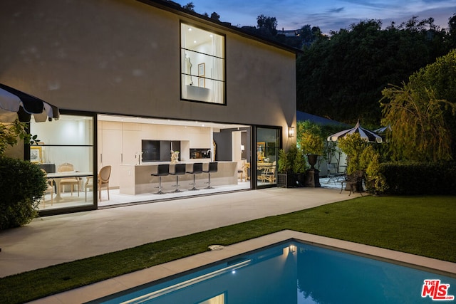 back house at dusk with a yard and a patio area