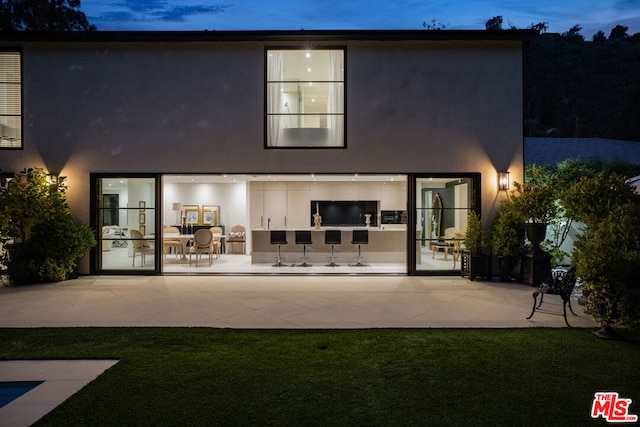 back house at dusk with a patio area