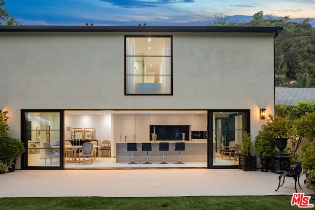 back house at dusk with a patio area