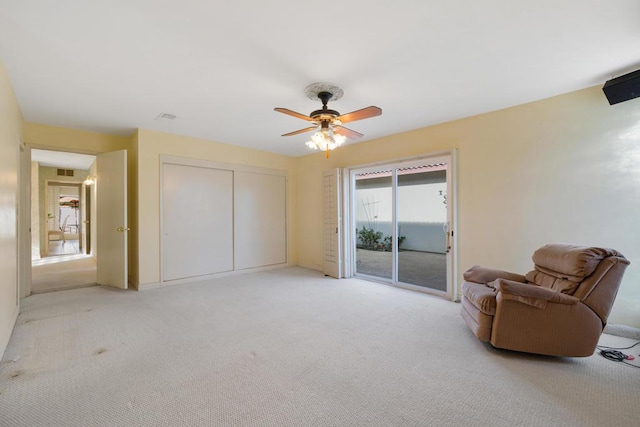 living area with light carpet and ceiling fan