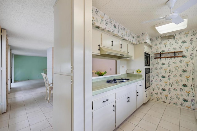 kitchen with light tile patterned floors, built in microwave, white cabinets, and oven