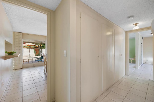 hall featuring a textured ceiling and light tile patterned floors