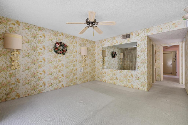 carpeted spare room featuring ceiling fan and a textured ceiling