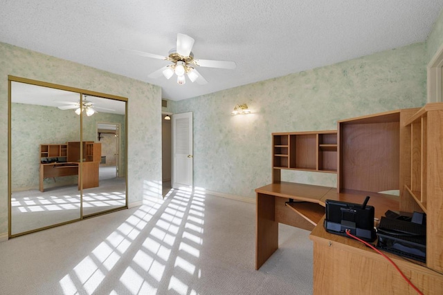 carpeted home office featuring a textured ceiling and ceiling fan