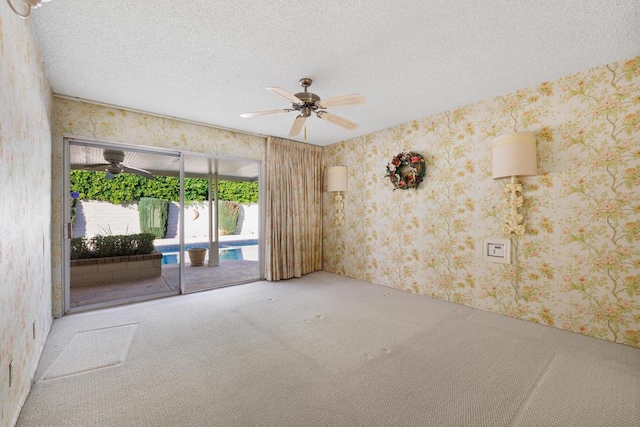 carpeted empty room with ceiling fan and a textured ceiling