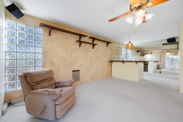 living area featuring ceiling fan, heating unit, and light carpet