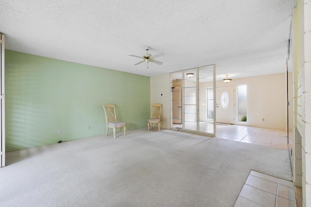 carpeted empty room featuring ceiling fan and a textured ceiling