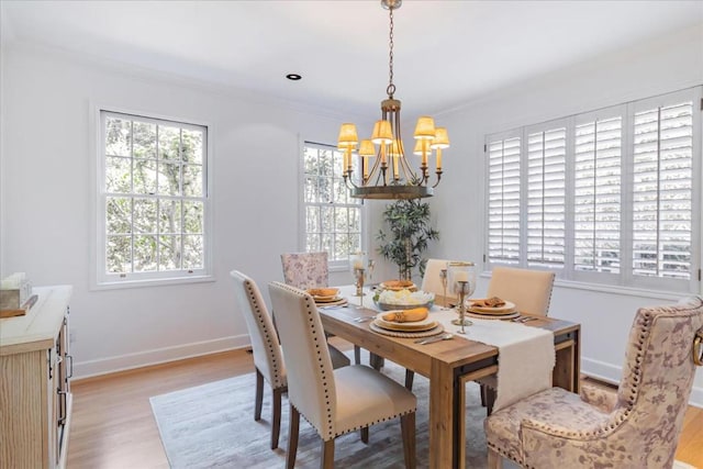 dining room featuring crown molding, a chandelier, a wealth of natural light, and light hardwood / wood-style floors