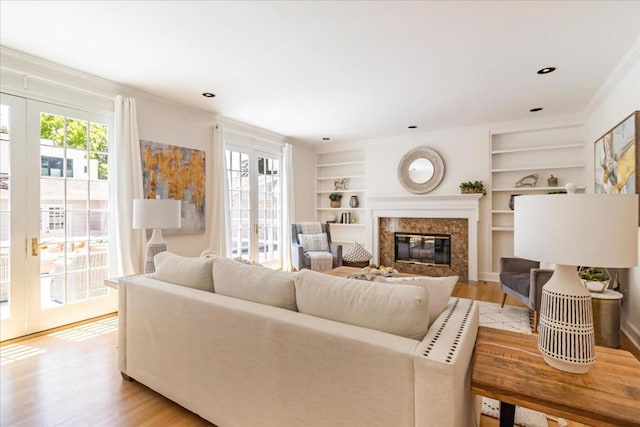 living room featuring built in shelves, french doors, light hardwood / wood-style flooring, and a wealth of natural light