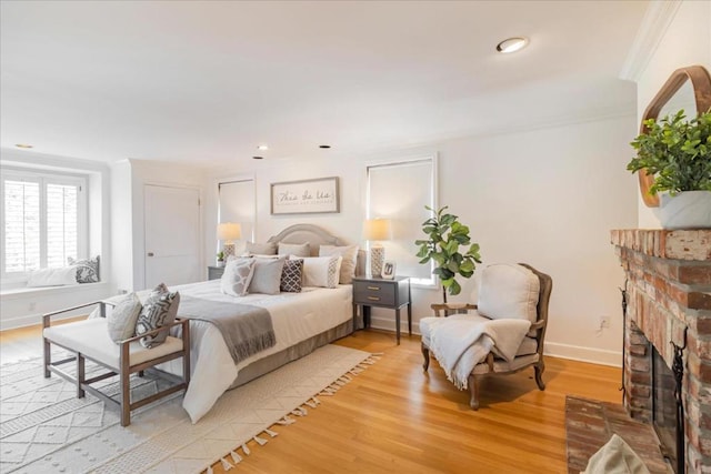 bedroom featuring crown molding, a fireplace, and light hardwood / wood-style floors