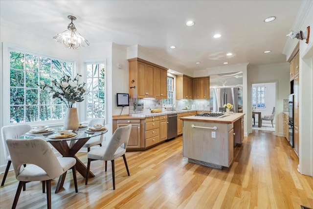 kitchen featuring a kitchen island, a wealth of natural light, decorative light fixtures, backsplash, and stainless steel appliances